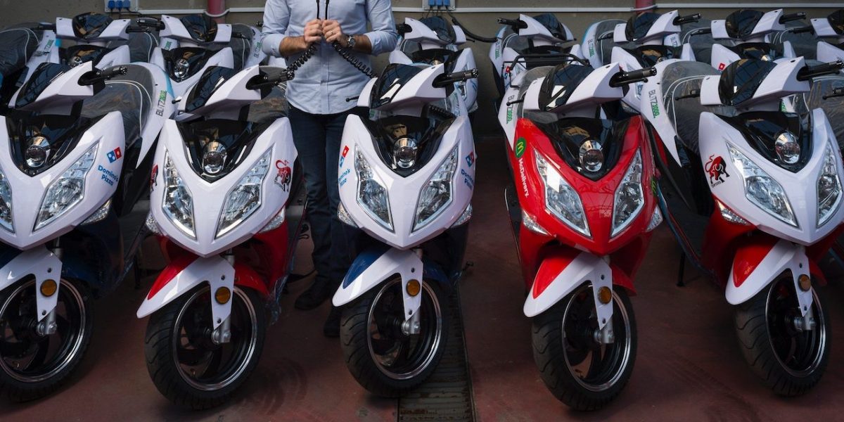 A row of mopeds with a man standing in the middle