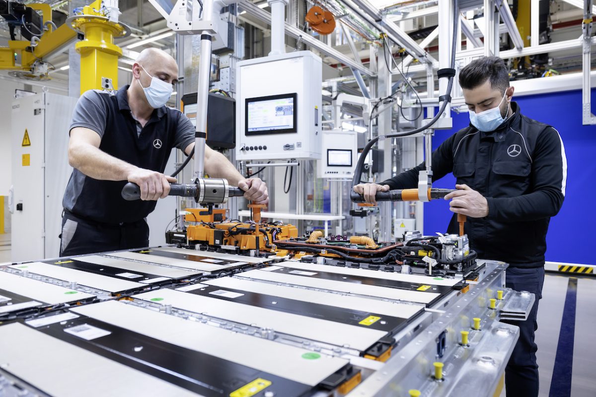 Two industrial workers creating EV batteries